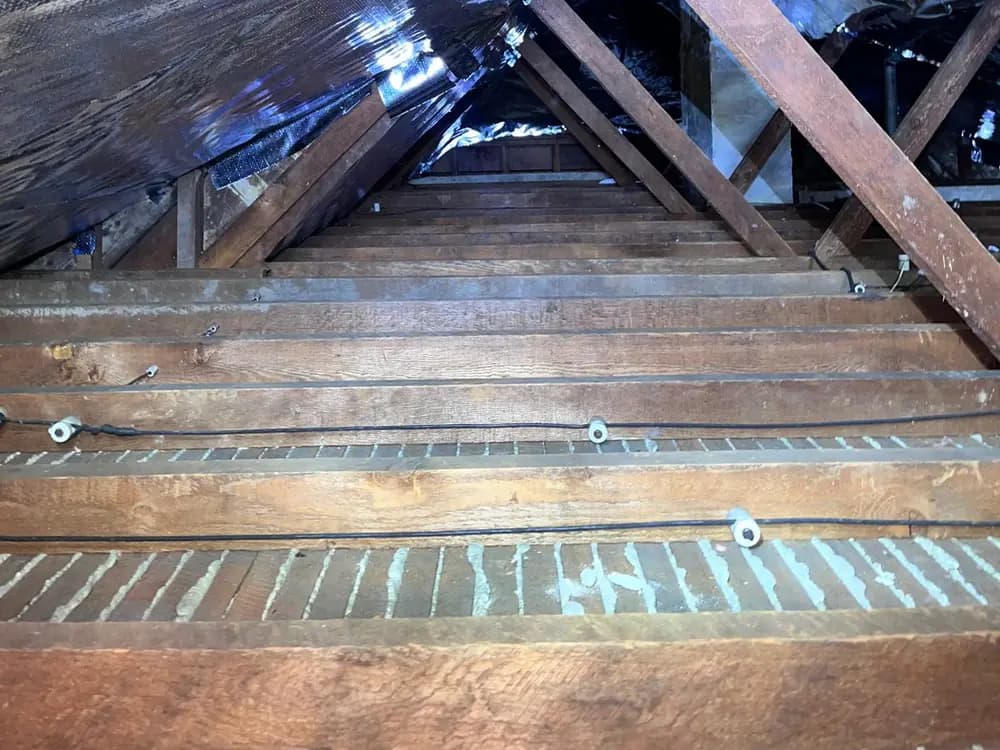 Partially installed radiant barrier at the roof line, above an attic ceiling plane where the joints have been sealed.