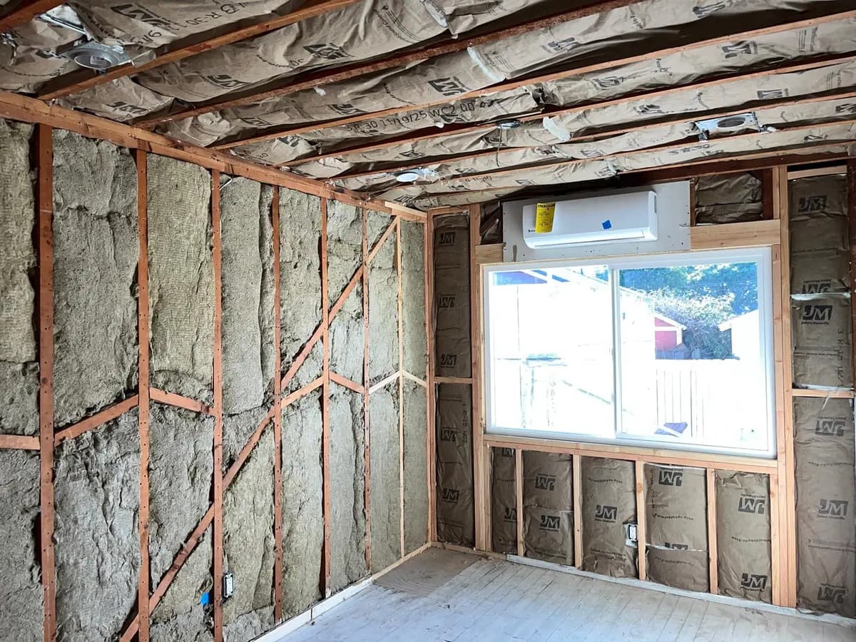 Faced batt insulation fitted between framing members in an open ceiling during a remodel.