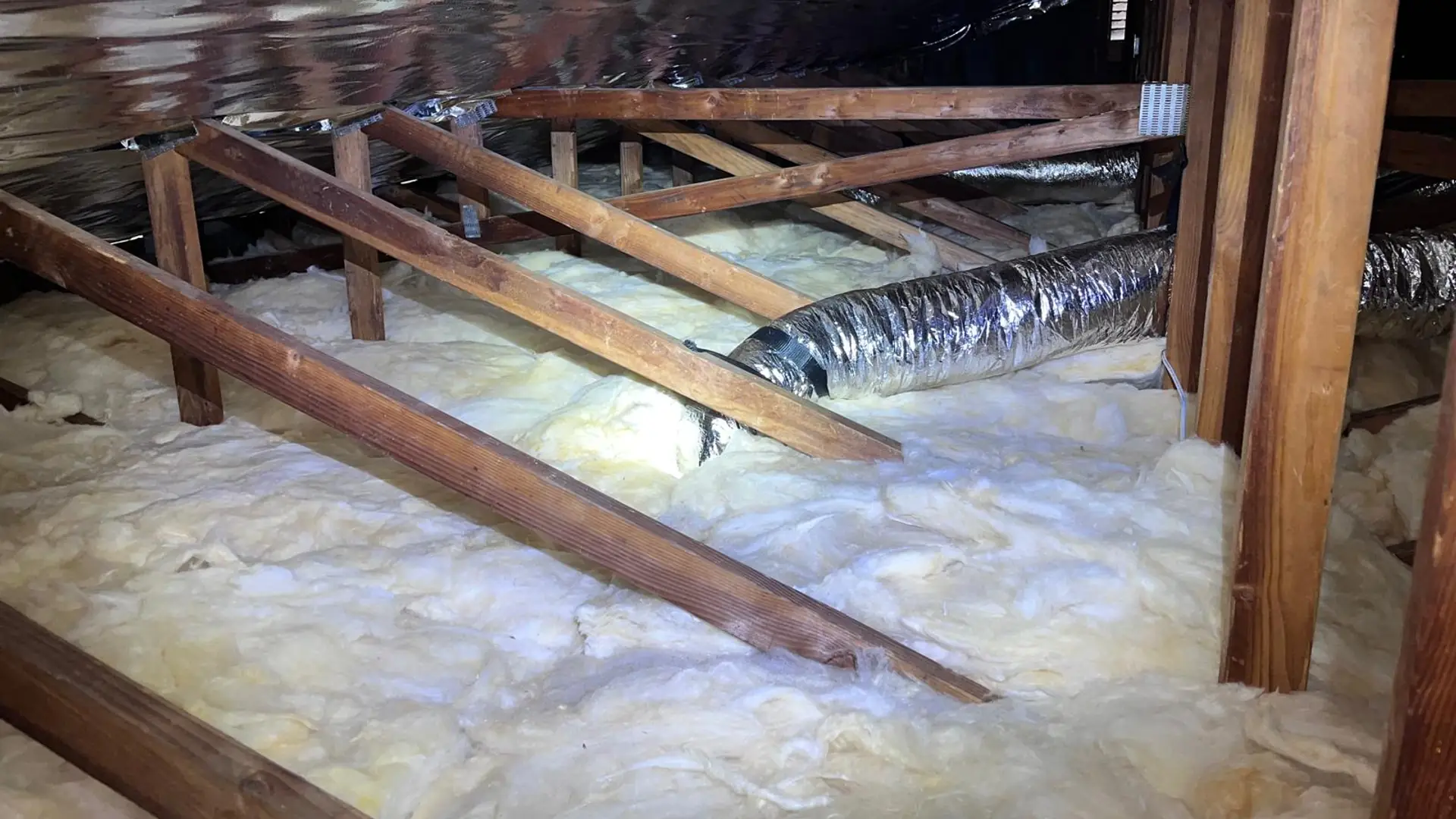 Piso de ático aislado de forma pareja entre las vigas, con una barrera radiante instalada arriba, a la altura del techo.